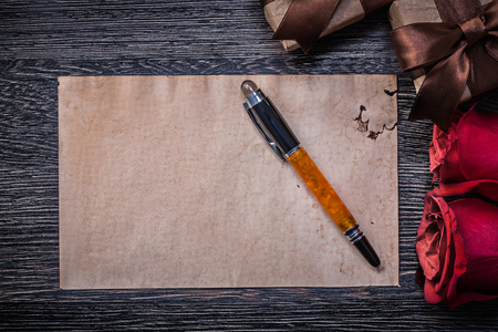 Vintage paper red roses giftboxes fountain pen on wooden board.の写真素材