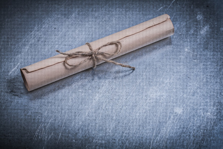 Vintage scroll of paper on scratched metallic surface.の写真素材