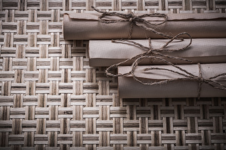 Vintage paper rolls on wicker wooden mat top view.