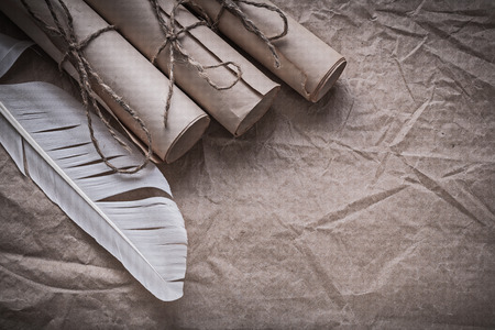 Stack of vintage paper scrolls quill on crumpled wrapping sheet.の写真素材