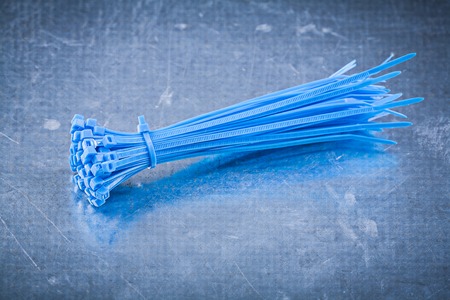 Blue plastic self-locking cable ties on metallic background construction concept.