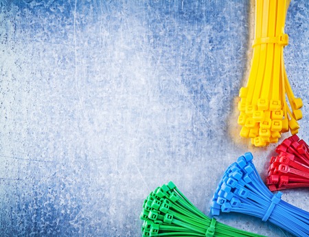Assortment of multicolored plastic cable ties on scratched metallic background.の写真素材