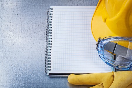 Safety glasses gloves copybook building helmet on scratched metallic background.の写真素材