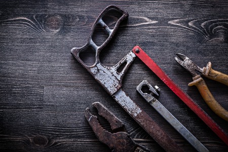 Obsolete vintage handsaw wire-cutter pliers on wooden board construction concept.の写真素材