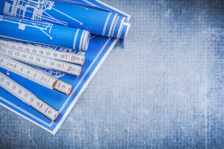 Blue construction plans wooden meter on metallic background maintenance concept.