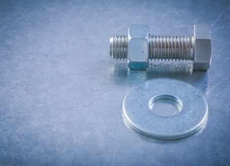 Metal bolt washer screwbolt nut on scratched metallic background.