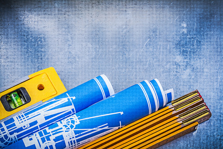 Wooden meter blue rolled construction plans level on metallic background.の写真素材
