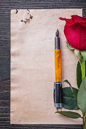 Vintage paper red scented rose fountain pen on wooden board.の写真素材