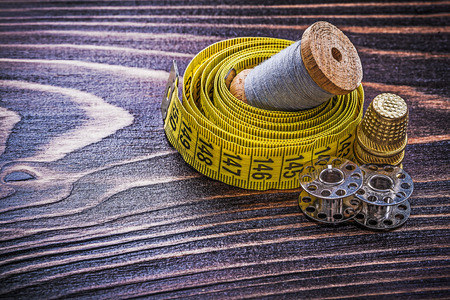Vintage reel of thread measuring tape thimble spools on wooden board handicraft concept.の写真素材