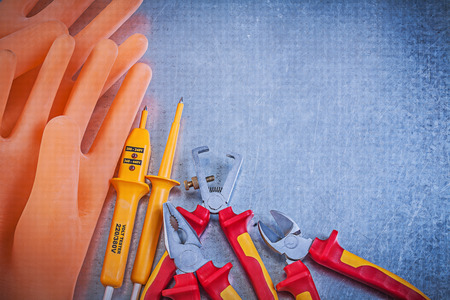 Insulating rubber gloves insulated wire strippers electrical tester pliers nippers on metallic...