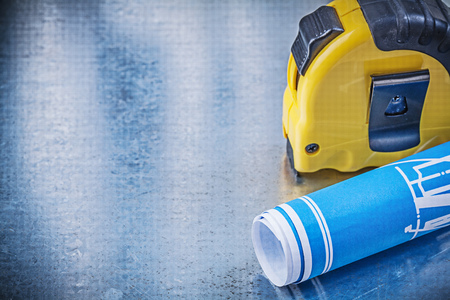 Blue engineering drawings tape measure on metallic background construction concept.