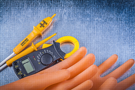 Digital ammeter electric tester dielectric rubber gloves on metallic background electricity concept.の写真素材