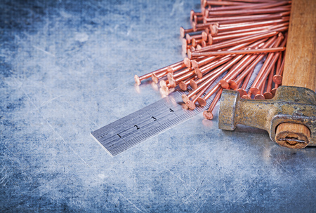Vintage claw hammer copper construction nails metal ruler on metallic background.の写真素材