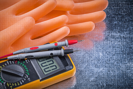 Digital electrical tester insulating rubber gloves on metallic background.の写真素材
