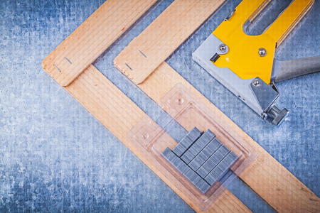 Collection of stapler gun metal staples wooden building board on metallic background.の写真素材