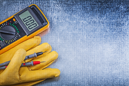 Digital electric tester safety gloves on metallic background electricity concept.の写真素材