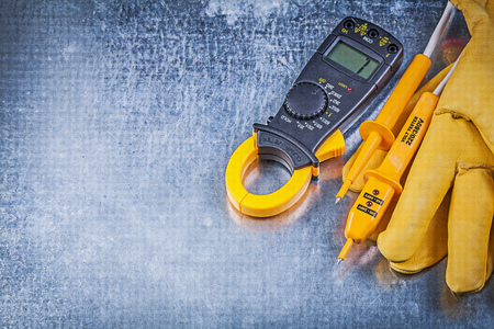 Digital ammeter electric tester protective gloves on metallic surface electricity concept.の写真素材