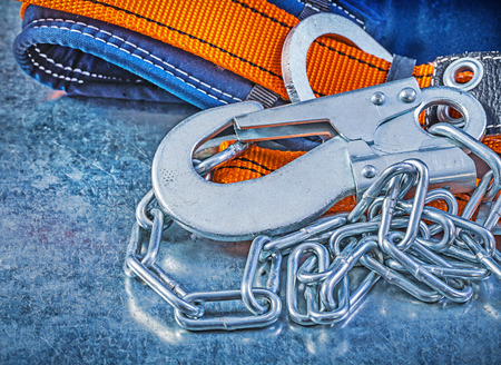 Safety harness metal chain carabiner hook on metallic background.