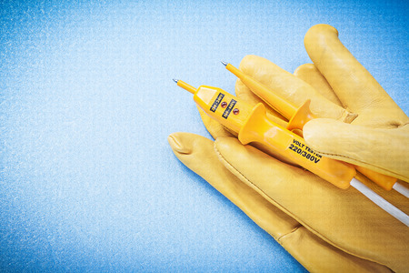 Leather yellow protective gloves electrical tester on blue background electricity concept.の写真素材
