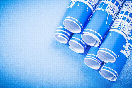 Stack of engineering drawings on blue background top view.