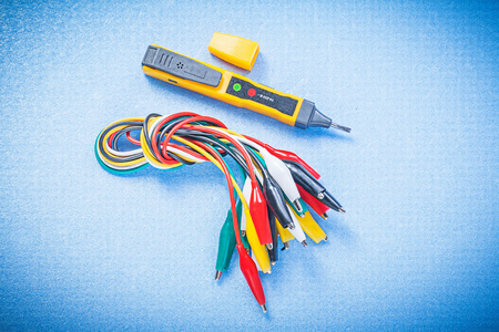 Electrical tester indicator crocodile plugs on blue background electricity concept.