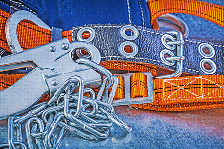 Construction harness metal chain carabiner hook on metallic background top view.