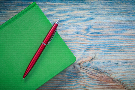 Closed green notebook pen on wood board education concept.の写真素材