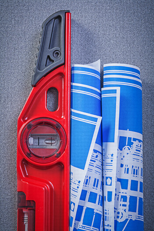 Construction level blue engineering drawings on grey background maintenance concept.