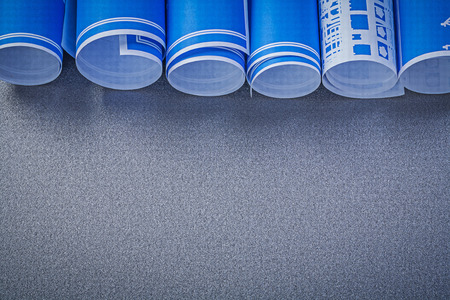 Stack of blue engineering drawings on grey background copy space construction concept.
