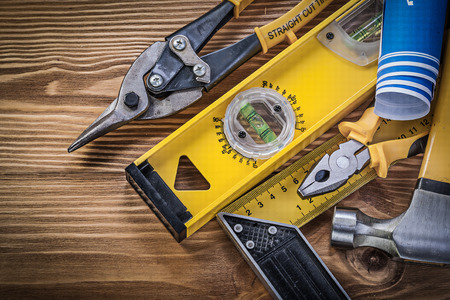Blue blueprints construction level square ruler claw hammer pliers steel cutter on wooden board.の写真素材