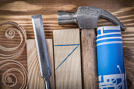 Blue rolled construction drawing claw hammer firmer chisel wooden studs curled shavings on vintage...