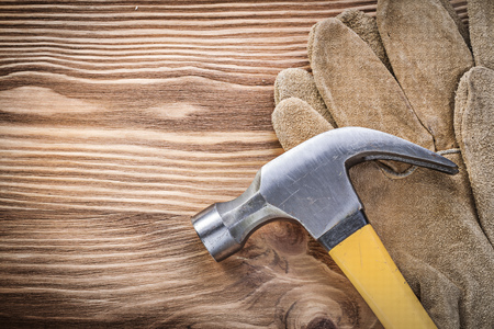 Leather safety gloves claw hammer on wooden board construction concept.の写真素材