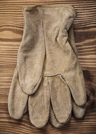 Leather safety gloves on vintage wooden board construction concept.