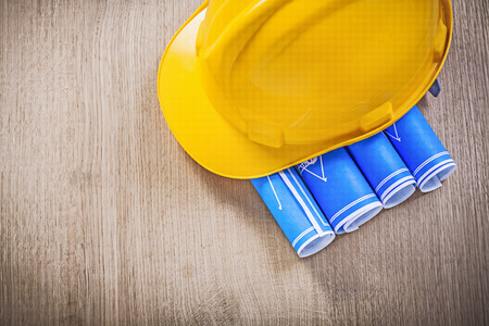 Wooden board with blue blueprints hard hat construction concept.