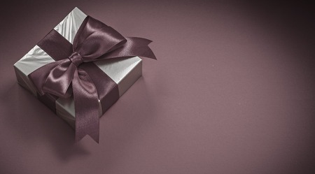 Present box with tied bow on red background holidays concept.の写真素材