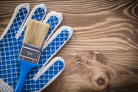 Pair of protective gloves paint brush on wooden board construction concept.の写真素材
