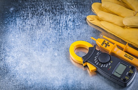 Digital clamp meter electrical tester protective gloves on metallic background electricity concept.の写真素材