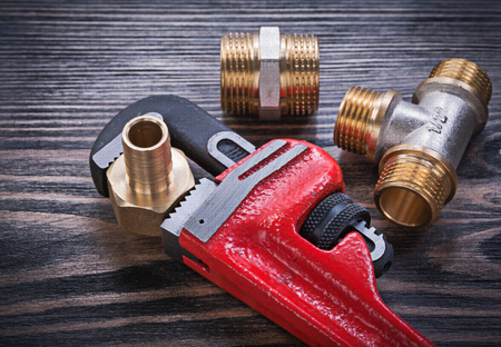 Monkey wrench brass equal tee nipple hose connectors on wooden board.の写真素材
