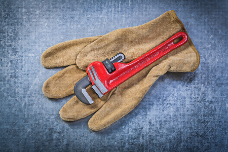 Monkey wrench leather protective gloves on scratched metallic background plumbing concept.の写真素材