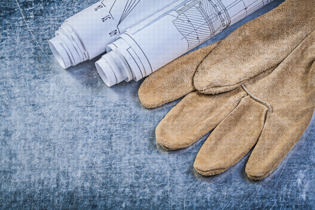 Rolled engineering drawings leather safety gloves on metallic background construction concept.の写真素材