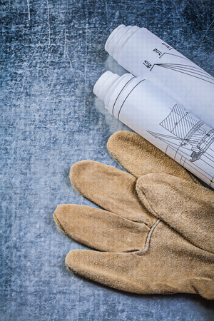 Rolled construction drawings leather safety gloves on metallic background top view.の写真素材