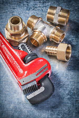 Pipe wrench brass nipple hose connectors on scratched metallic background plumbing concept.の写真素材