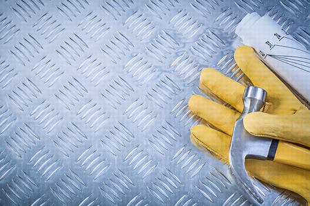 Claw hammer protective gloves rolled engineering drawings on grooved metal plate copy space...