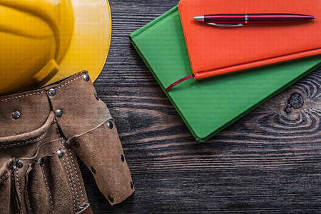 Assortment of tool belt notepads pen hard hat on wooden board construction concept.の写真素材