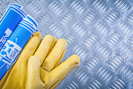 Blue engineering drawings leather protective gloves on grooved metal plate construction concept.の写真素材