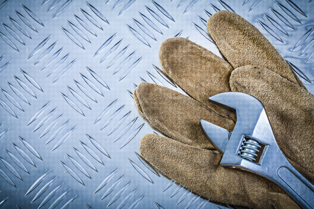 Safety gloves adjustable wrench on grooved metal plate construction concept.の写真素材