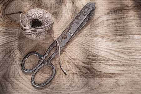 Skein of rope vintage scissors on wooden board.