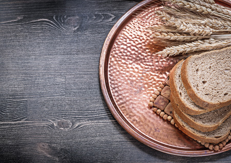 Rye wheat ears sliced loaf of bread vintage copper tray food and drink concept.