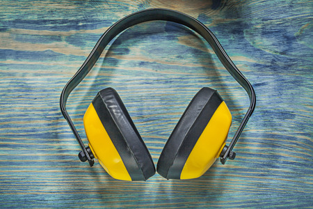 Noise reduction ear muffs on wooden board construction concept.