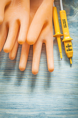 Electric tester electricians gloves on wooden board electricity concept.の写真素材